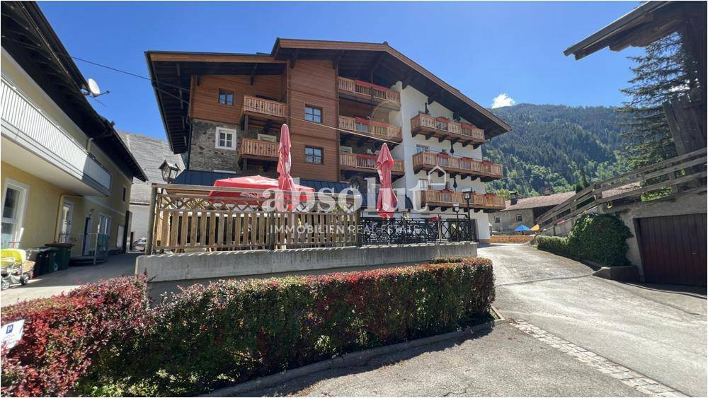 Großes Gebäude im alpinen Stil mit Holzbalkonen und einer Terrasse im Vordergrund.