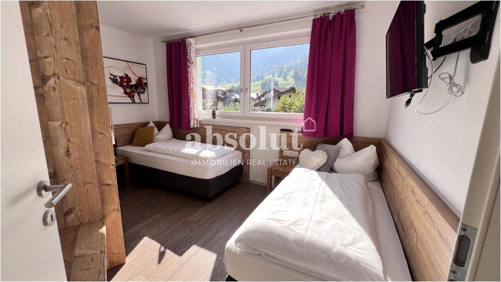 Helles Schlafzimmer mit zwei Einzelbetten, Holzelementen und Blick auf die Berge.