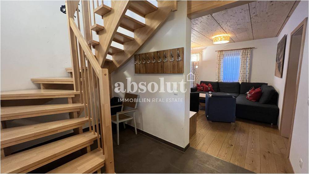 Heller Eingangsbereich mit Holztreppe und Blick in den Wohnbereich.