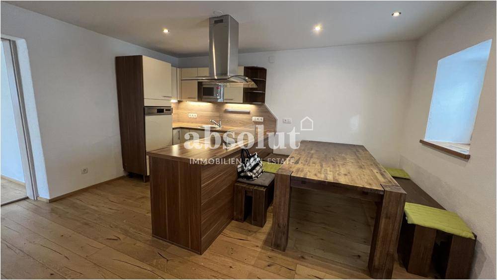Moderne Küche mit Holztisch, Einbaugeräten und direktem Zugang zum Essbereich.