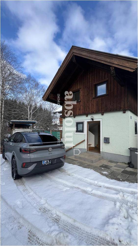 Außenansicht eines Hauses mit Holzfassade und verschneiter Auffahrt.