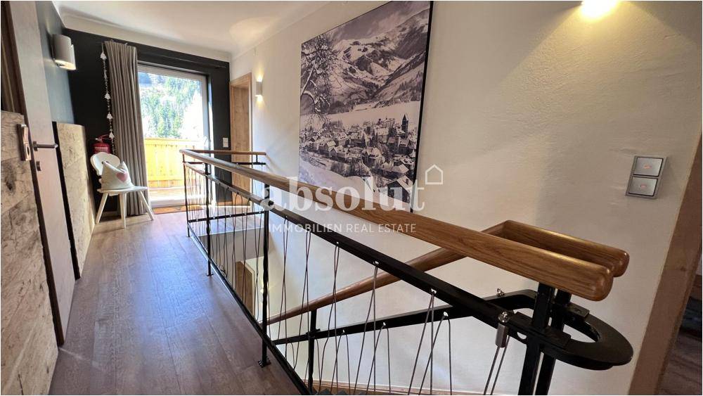 Heller Treppenaufgang mit Holzgeländer und Blick auf den Balkon, verbindet die Etagen.