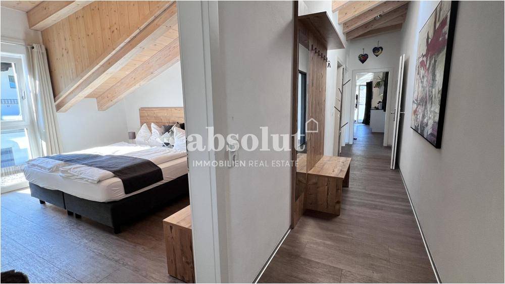 Gemütliches Schlafzimmer mit Holzbalkendecke und Zugang zu einem Flur mit Garderobe.