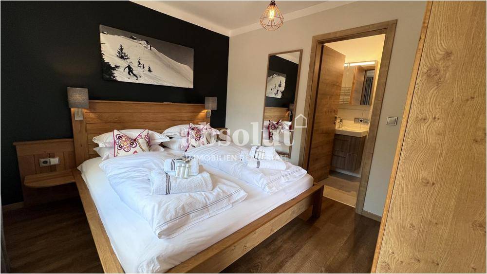 Komfortables Schlafzimmer mit Holzbett und direktem Zugang zu einem modernen Badezimmer.