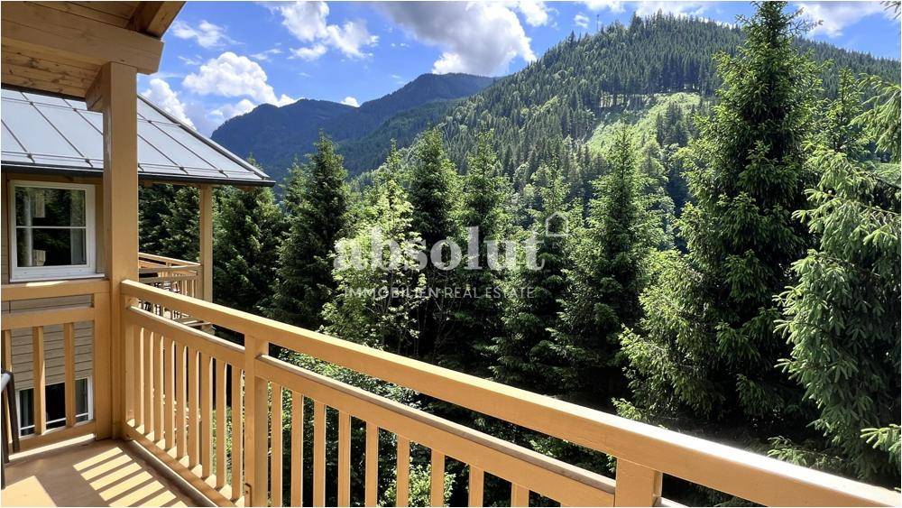 Balkon mit Holzbalkongeländer und Blick auf dichte grüne Wälder und Berge.