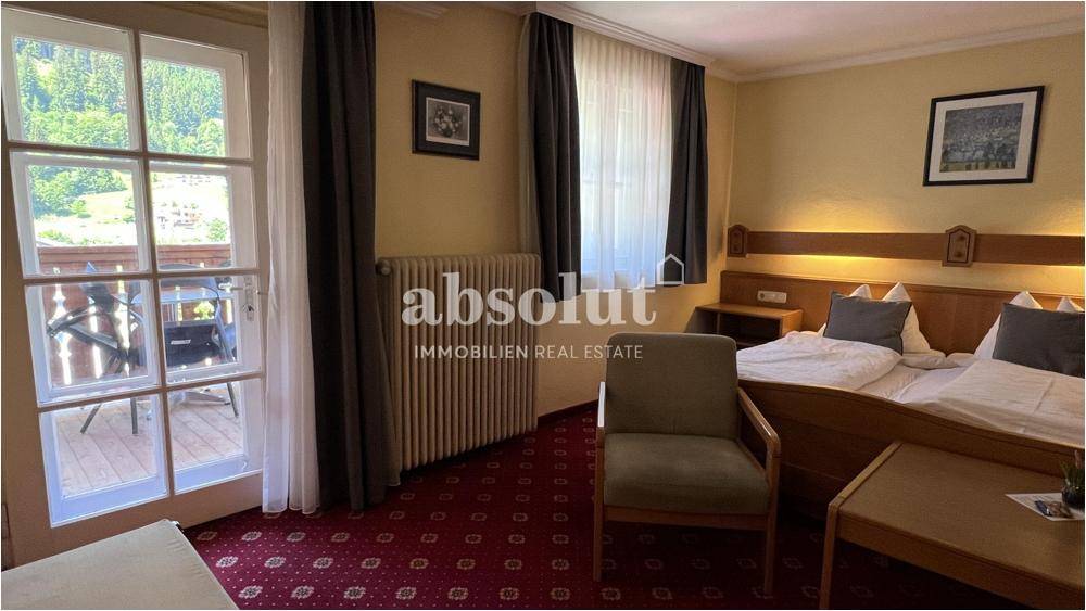 Helles Schlafzimmer mit Balkonzugang, zwei Betten und traditionellem Teppichboden.