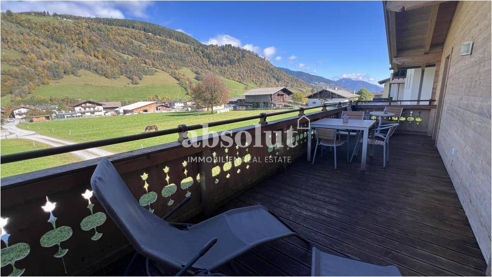 Geräumiger Holzbalkon mit Sitzgelegenheiten und Panoramablick auf die grüne Berglandschaft.