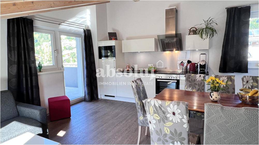 Offener Wohn- und Essbereich mit integrierter Küche und Zugang zu einem Balkon.