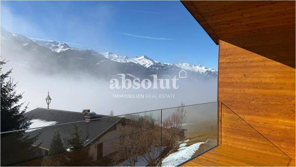 Panoramablick von einem Balkon auf nebelverhangene Berge und die umliegende Winterlandschaft.