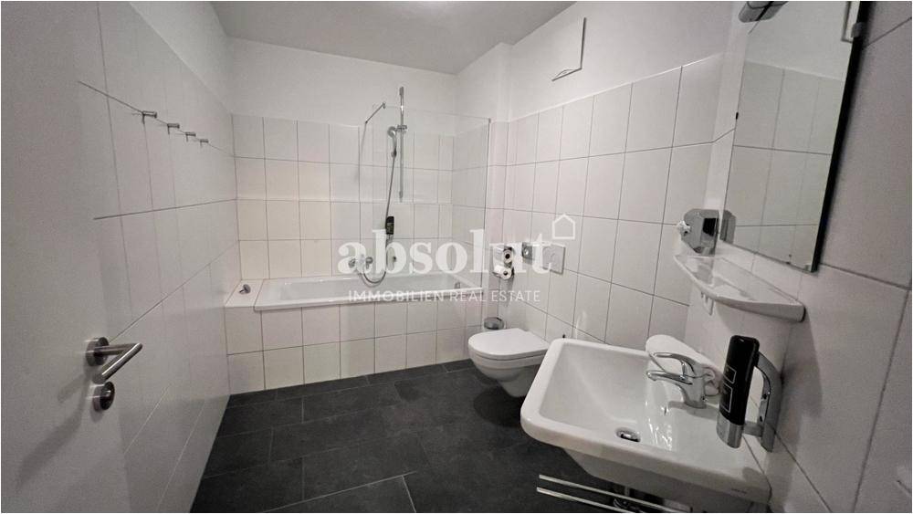 Helles Badezimmer mit Badewanne, Waschbecken und WC, ausgestattet mit weißen Fliesen und Spiegel.