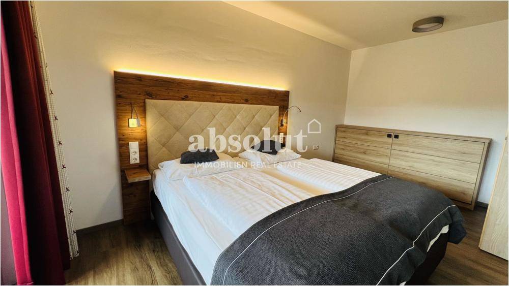 Komfortables Schlafzimmer mit großem Doppelbett, Holzboden und moderner Beleuchtung.