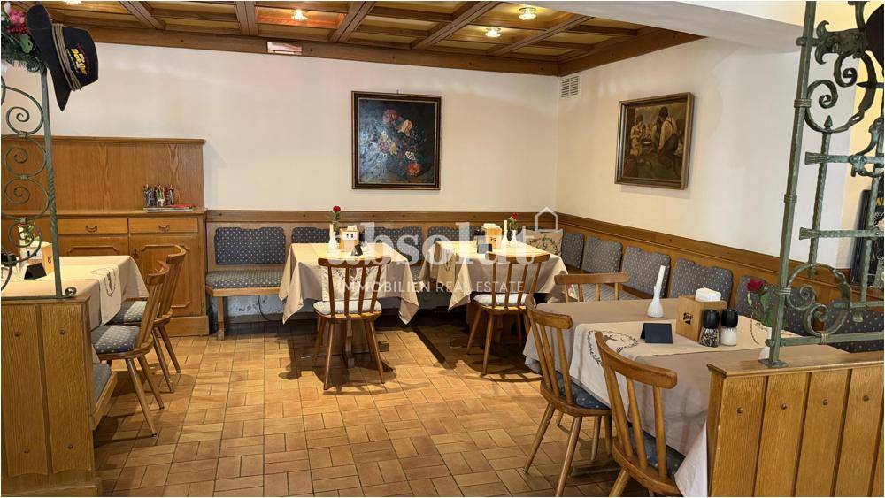 Gemütlicher Speisesaal mit Holztischen, gepolsterten Bänken und traditioneller Einrichtung.