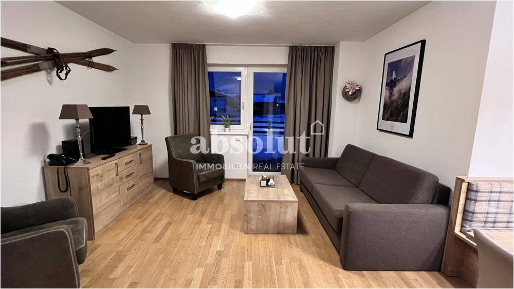 Gemütliches Wohnzimmer mit Holzboden, bequemen Sofas und Zugang zu einem Balkon für frische Luft.