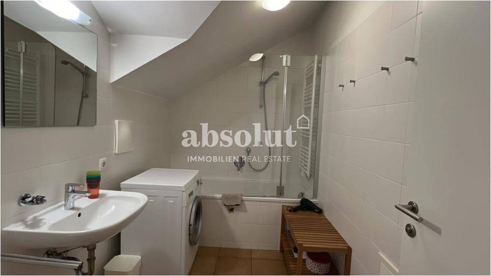Badezimmer mit Badewanne, integrierter Dusche und Waschmaschine.