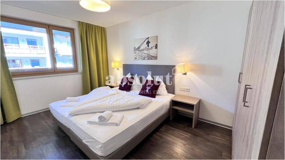 Helles Schlafzimmer mit großem Fenster, Doppelbett und schlichter, funktionaler Einrichtung.