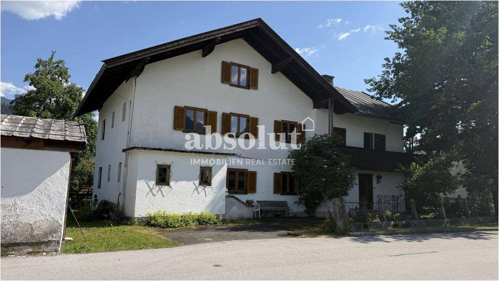 Vorderansicht eines traditionellen Hauses mit Holzfensterläden und einem kleinen Vorgartenbereich.