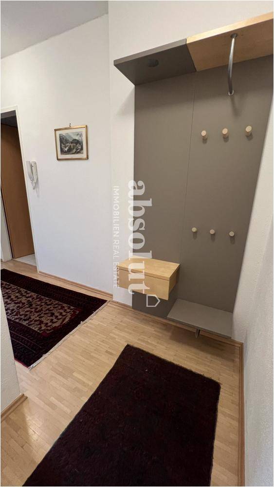 Heller Eingangsbereich mit Garderobe, Parkettboden und einem Teppichläufer, der zum Eintreten einlädt.