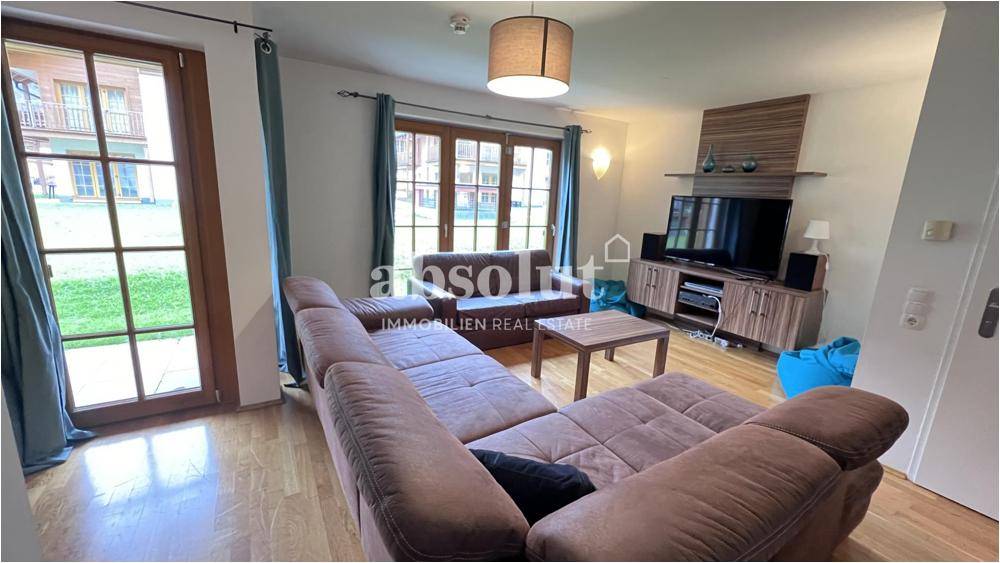 Wohnzimmer mit großem Sofa, Holzboden und direktem Zugang zum Gartenbereich.