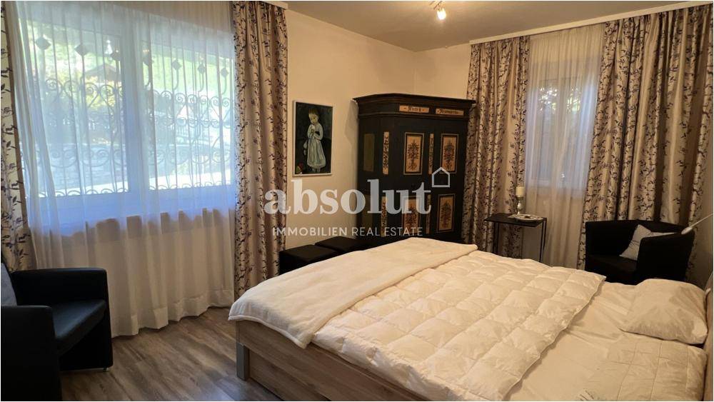 Gemütliches Schlafzimmer im traditionellen Stil mit großem Bett, Kleiderschrank und Fenstern mit Vorhängen.
