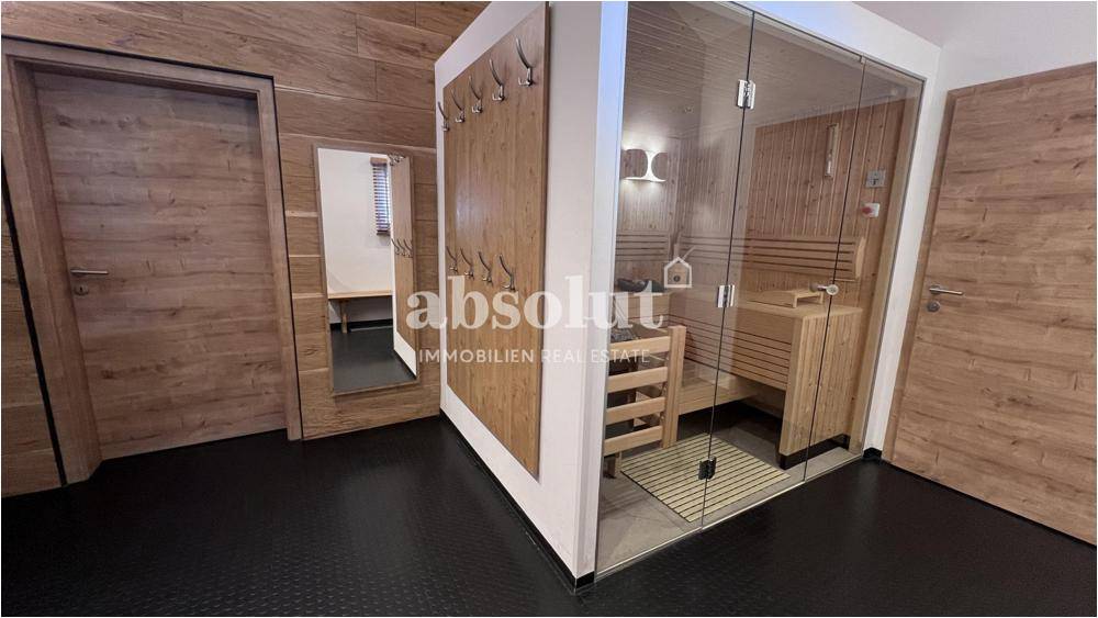 Moderner Wellnessbereich mit verglaster Sauna und Holzelementen für entspannende Stunden.