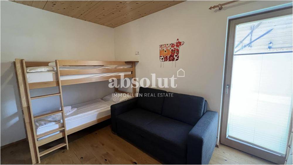 Gemütliches Schlafzimmer mit Etagenbett, Sofa und Holzboden, ideal für Gäste oder Kinder.