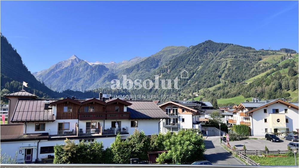 Weitläufiger Blick auf die alpine Umgebung mit traditionellen Häusern und majestätischen Bergen.