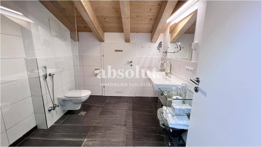 Modernes Badezimmer mit begehbarer Dusche, Waschtisch und Holzbalken an der Decke.