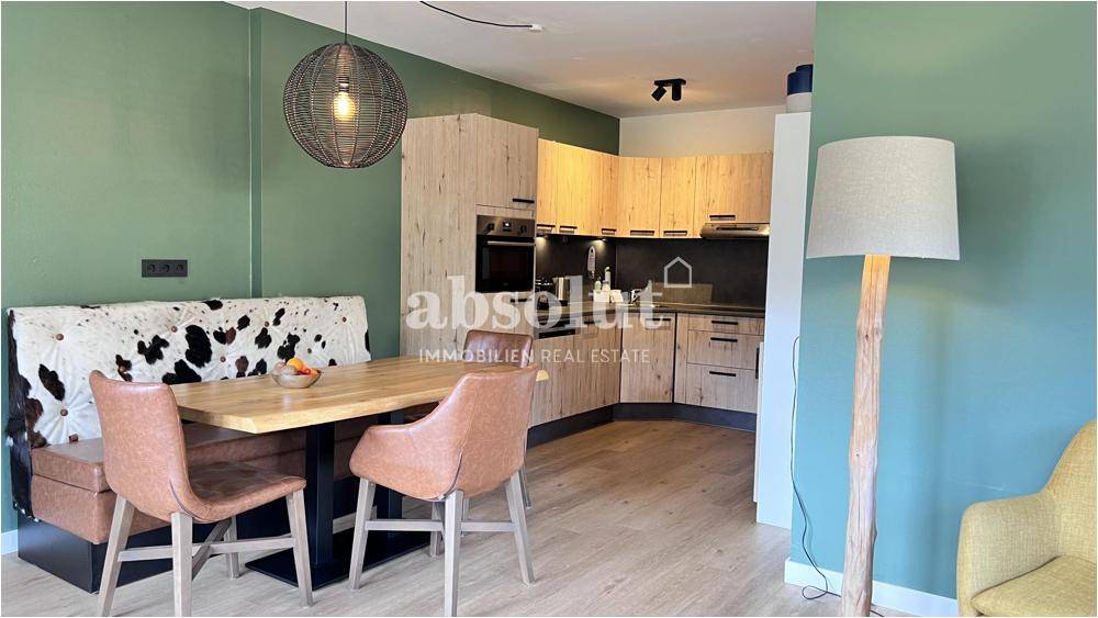 Moderne Küche mit Essbereich, Holzfronten und gemütlicher Sitzbank mit Kuhfellmuster.