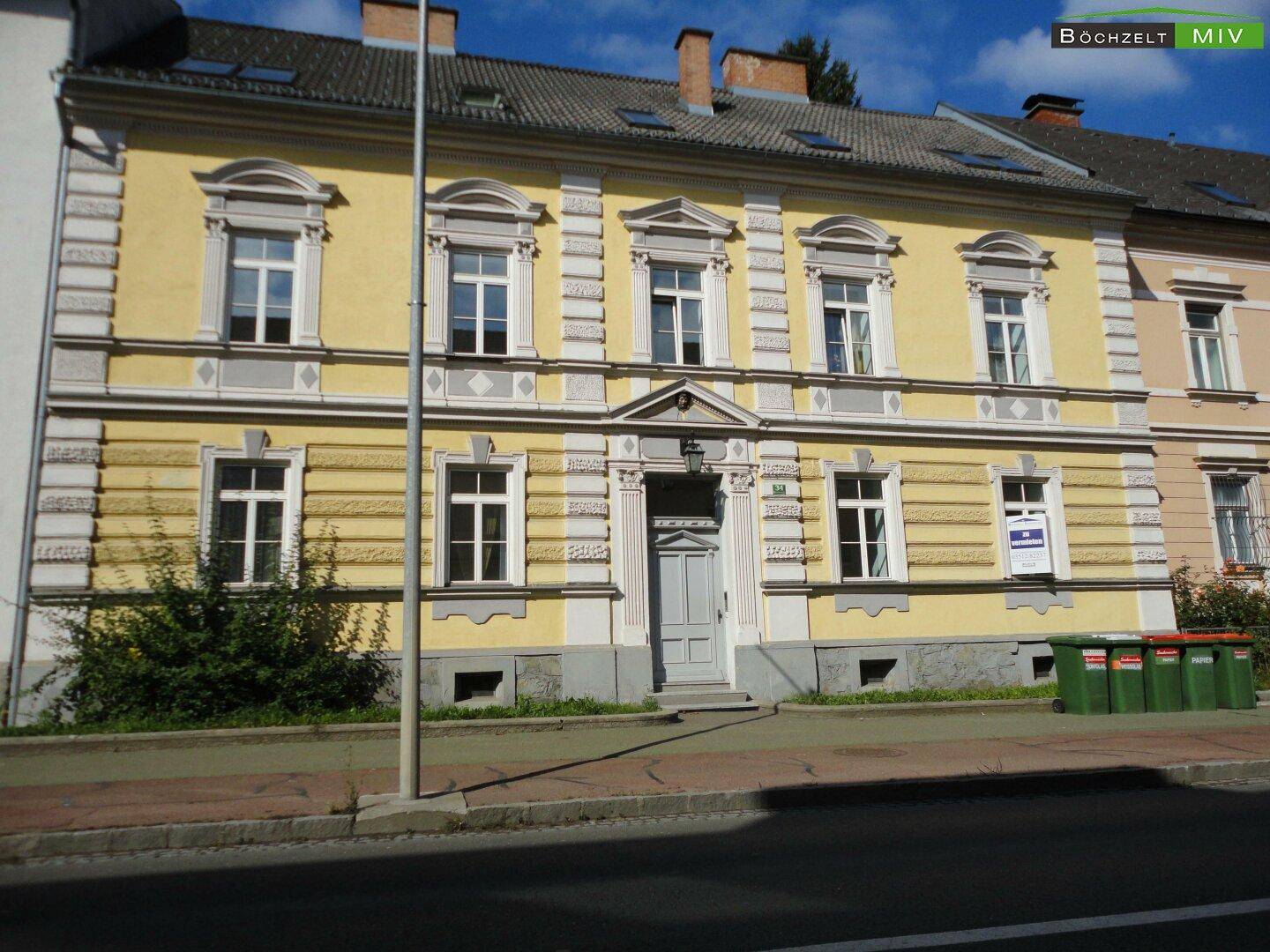 Historische gelbe Fassade eines Gebäudes mit dekorativen Elementen und mehreren Fenstern.