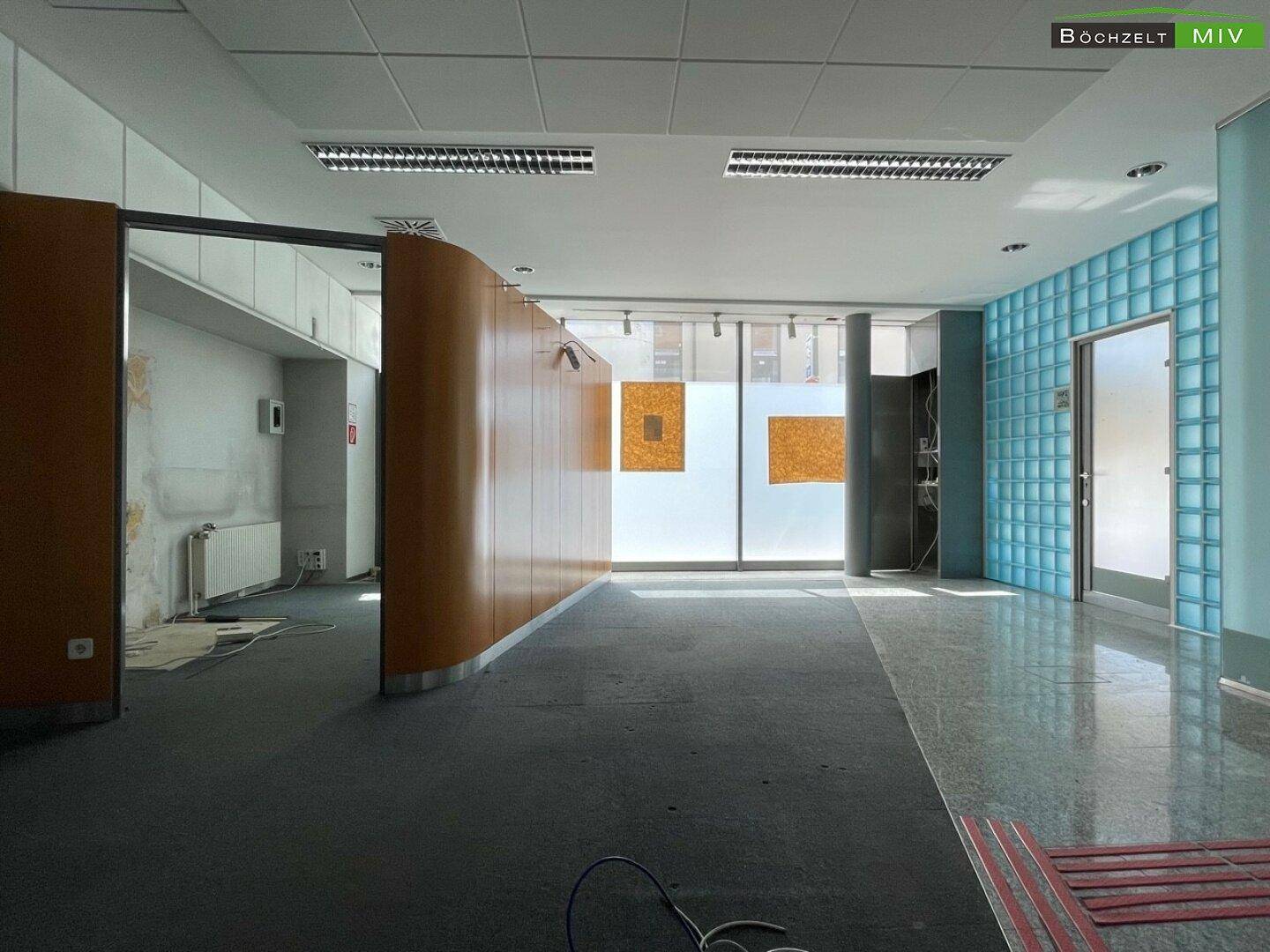 Großer Bürobereich mit geschwungener Holztrennwand, Glasbausteinwand und großen Fenstern.