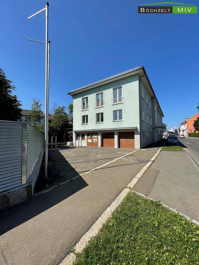 Gebäudeansicht von der Seite mit Garagentoren im Erdgeschoss und einem Laternenmast im Vordergrund.