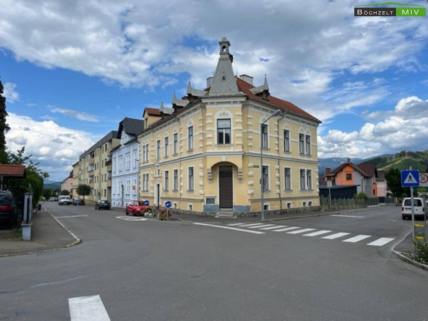 Historisches Eckgebäude mit markanter Architektur und gelber Fassade an einer Straße.