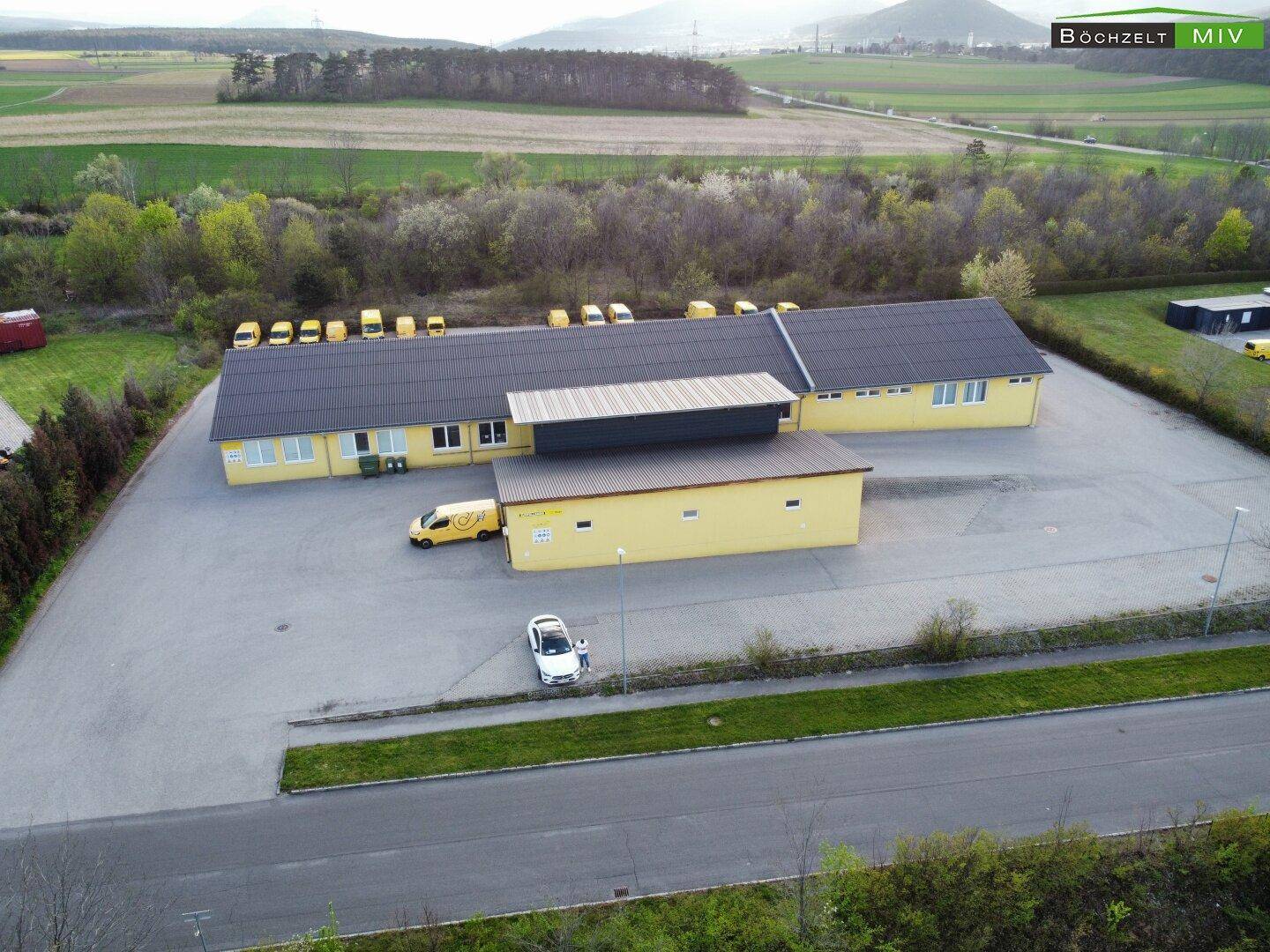 Weitläufige Luftaufnahme eines Gewerbeobjekts mit umliegender grüner Landschaft und Feldern.