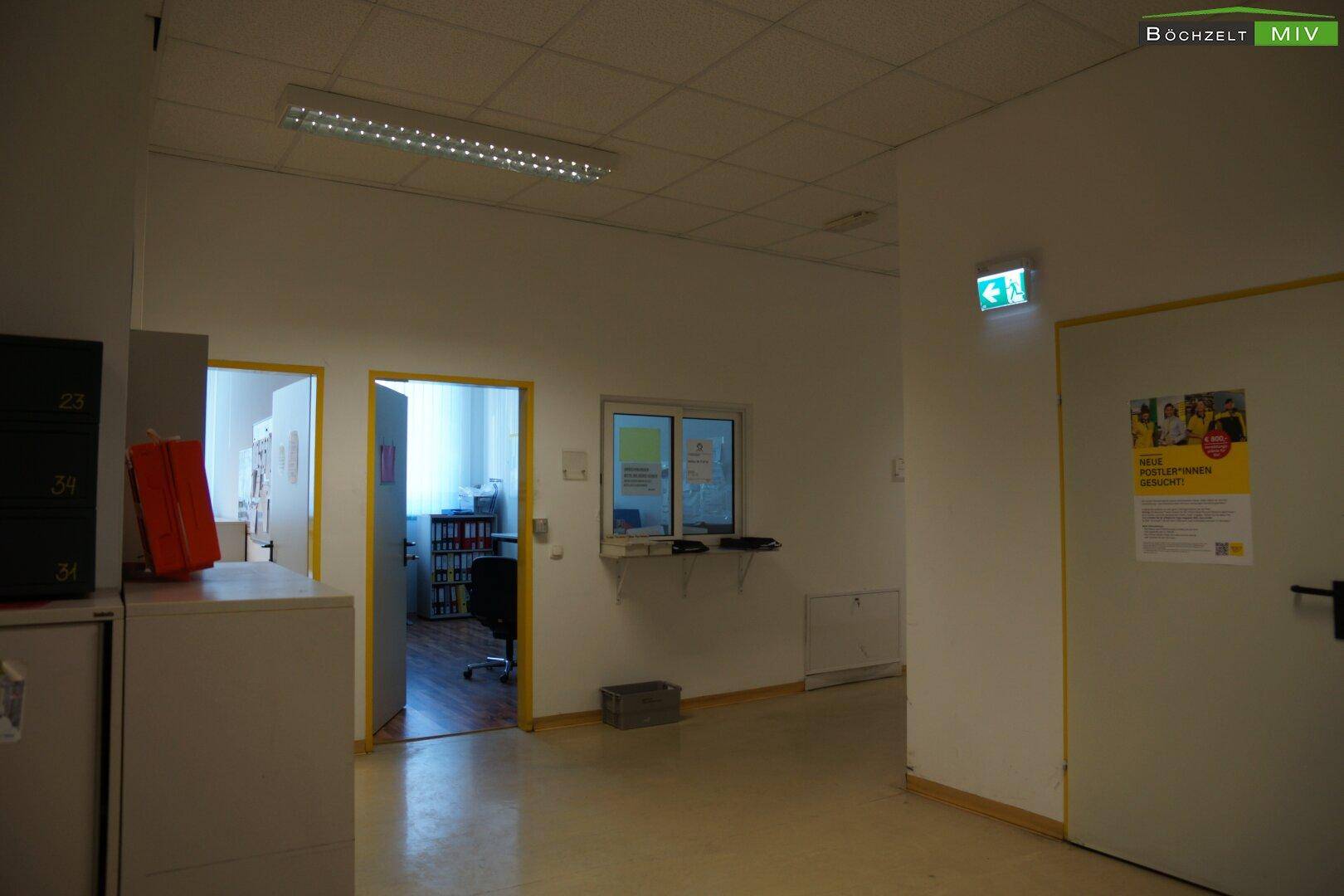 Empfangsbereich mit Serviceschalter und Zugang zu einem weiteren Büro, hell und funktional.