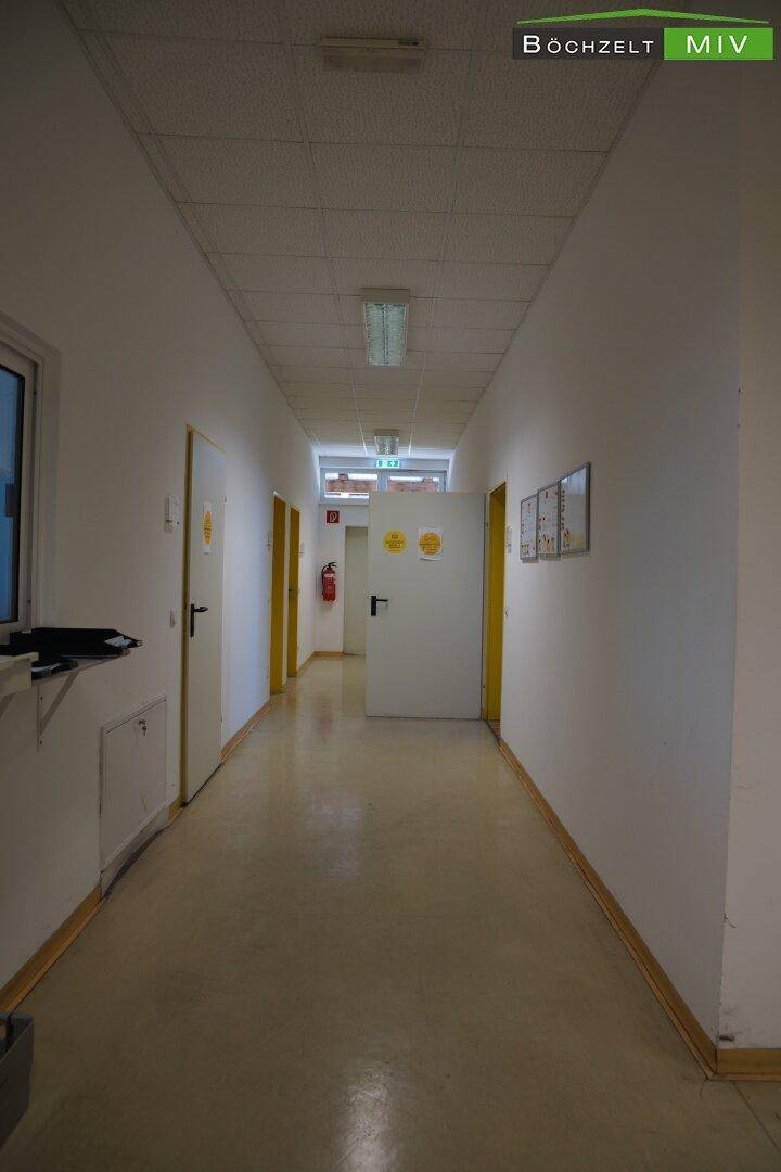 Langer, heller Flur mit mehreren Türen, der zu verschiedenen Büros oder Räumen führt.