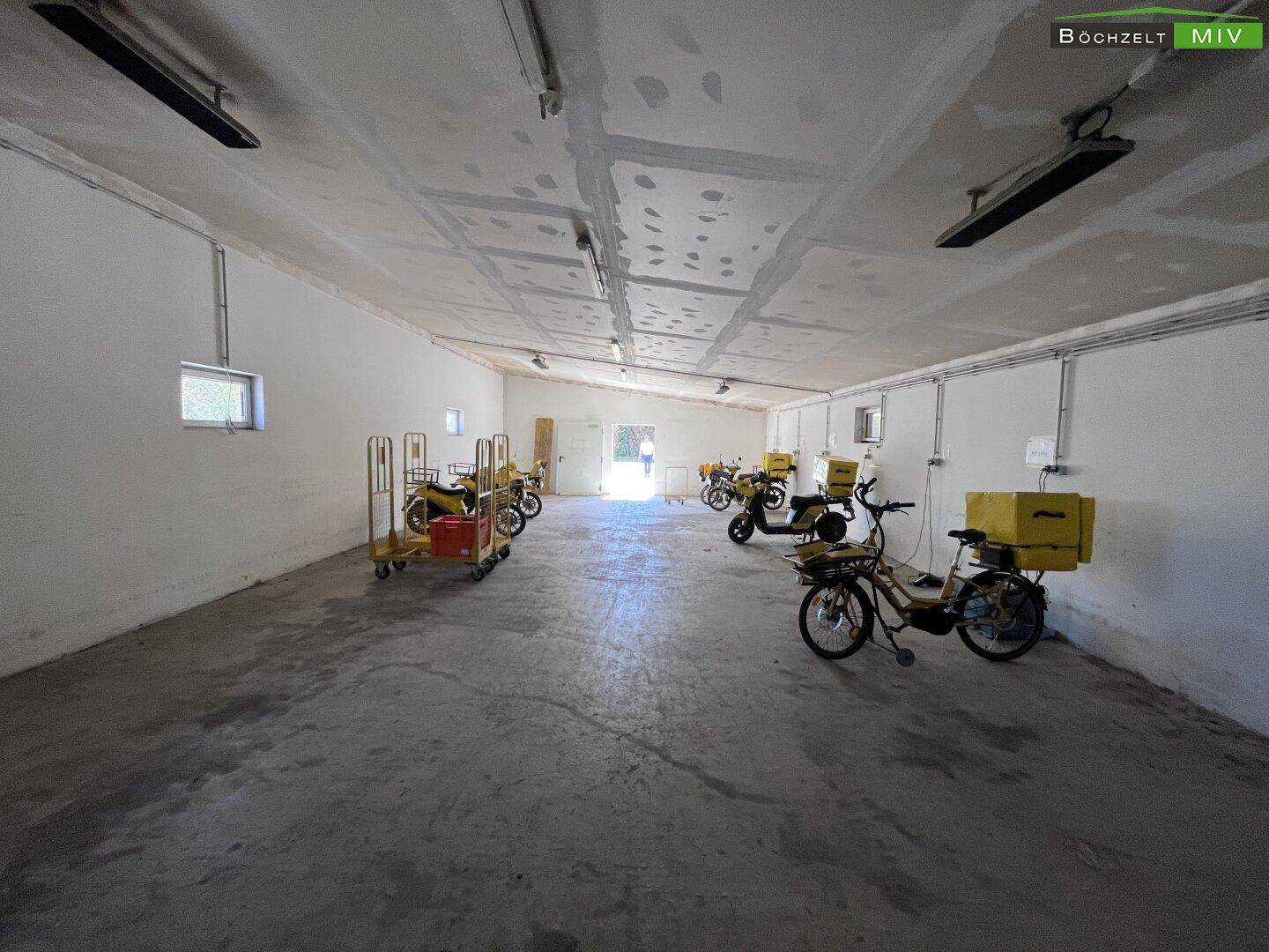 Geräumige Garage mit gelben Lieferfahrzeugen und viel freiem Platz für weitere Nutzung.