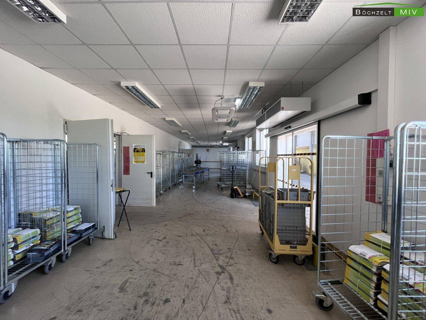 Großer, offener Arbeitsbereich mit vielen Gitterwagen und Sortierstationen, ideal für Logistik und Verteilung von Waren.
