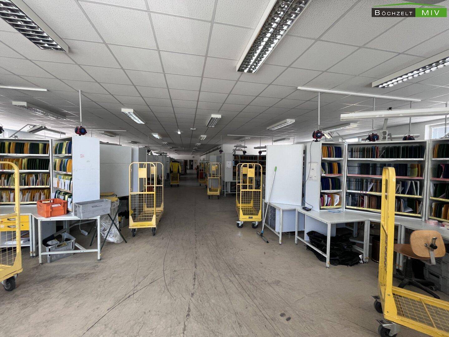 Langer Bürobereich mit mehreren Arbeitsplätzen und Sortierregalen, effizient für Teamarbeit und Organisation gestaltet.