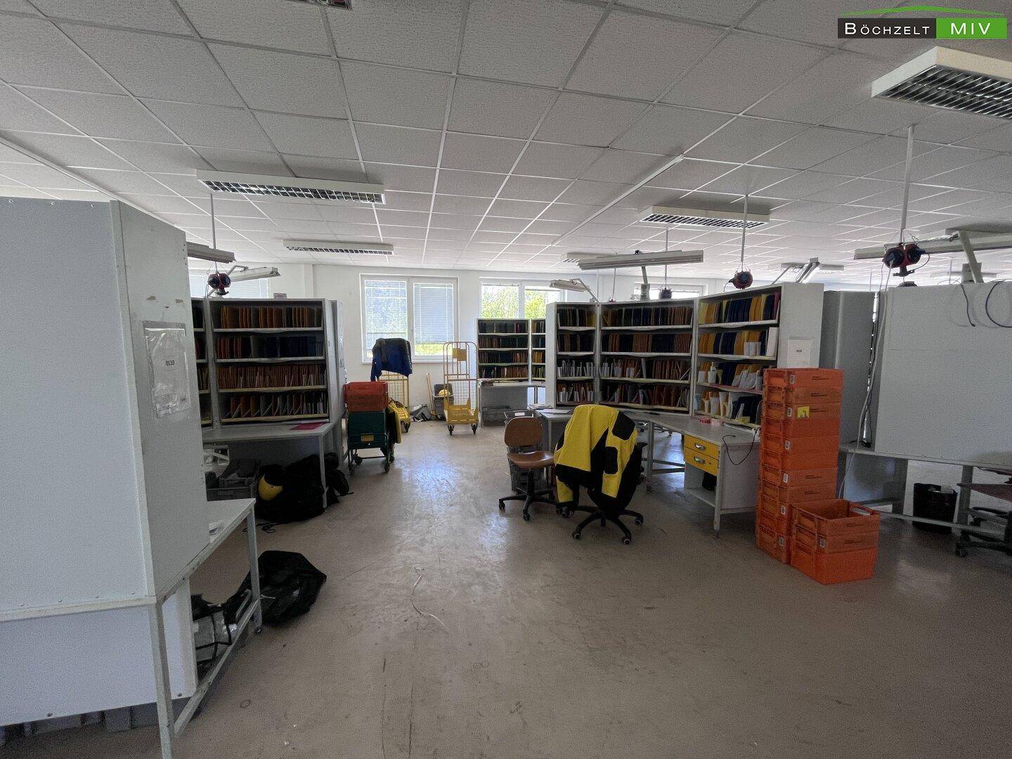 Geräumiger Bürobereich mit mehreren Arbeitsplätzen und Sortierregalen, ideal für große Teams und effizientes Arbeiten.