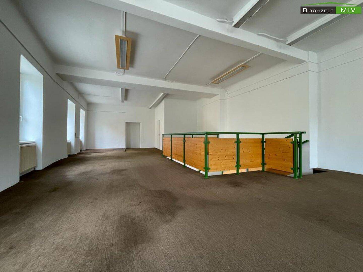 Geräumiger Obergeschossbereich mit Teppichboden und Holzgeländer, ideal für Ausstellungsflächen oder Büros.