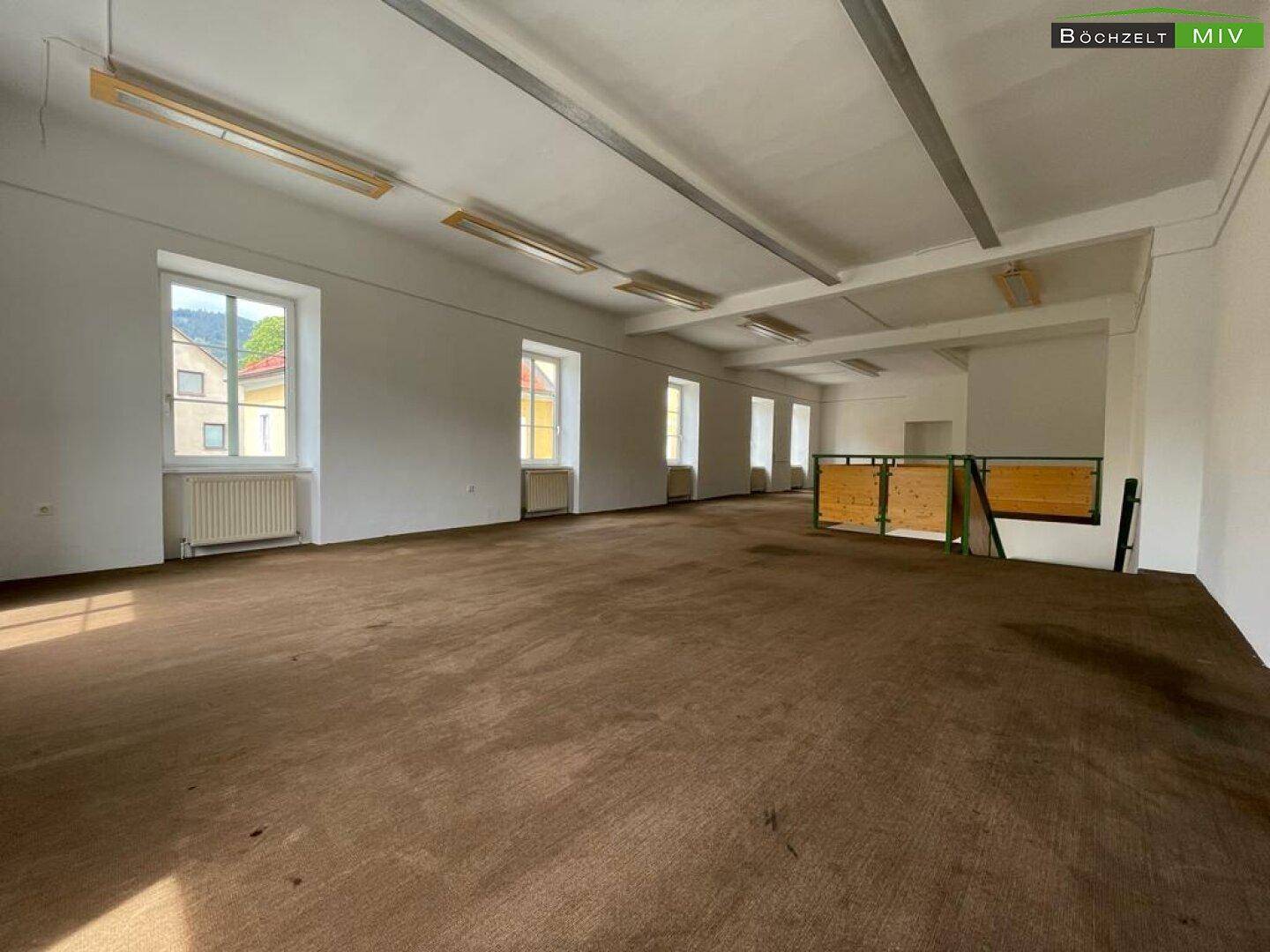 Weitläufiger Obergeschossbereich mit Teppichboden und einer Reihe von Fenstern für optimale Belichtung.