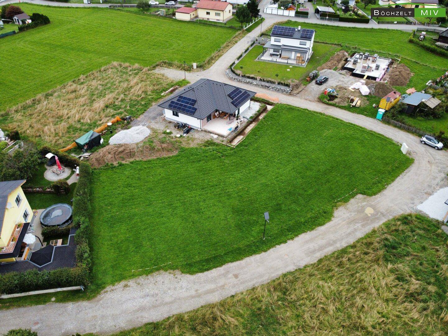 Luftaufnahme eines kürzlich fertiggestellten Hauses mit Photovoltaikanlage in einer idyllischen Wohngegend.