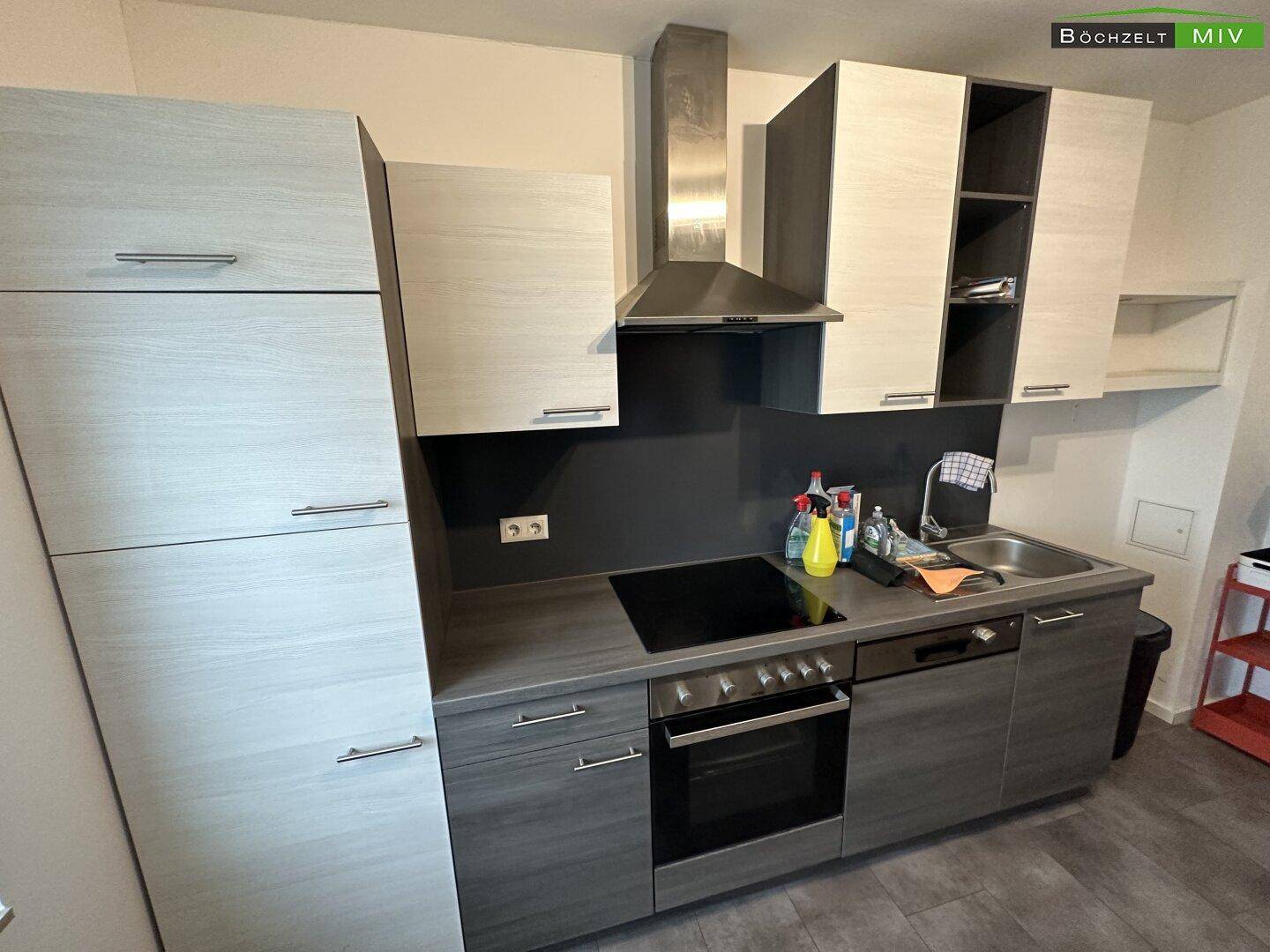 Moderne Einbauküche mit grauen und hellen Holzfronten, Induktionskochfeld, Backofen und Dunstabzugshaube.