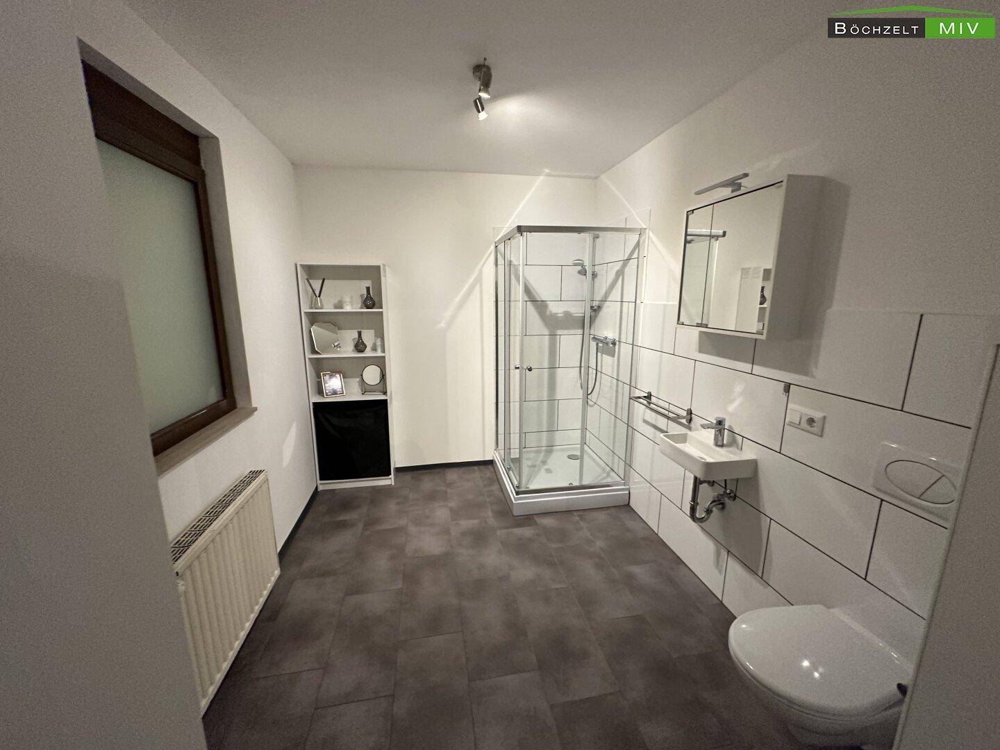 Geräumiges Schlafzimmer mit Bett, Duschkabine und Waschbecken, sowie einem Fenster für natürliche Belichtung.