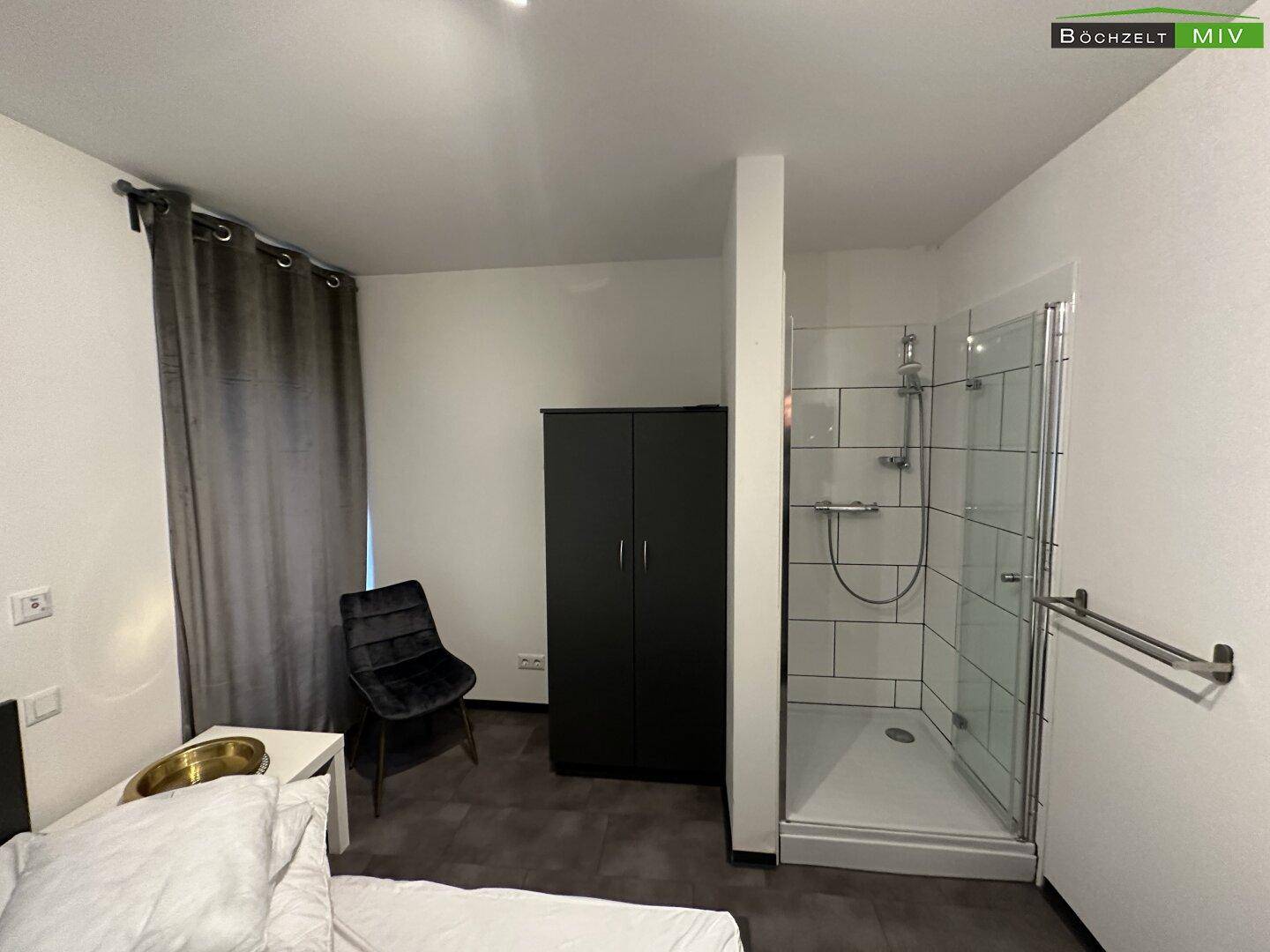 Schlafzimmer mit Bett, Kleiderschrank und einer integrierten Duschkabine, praktisch und modern gestaltet.