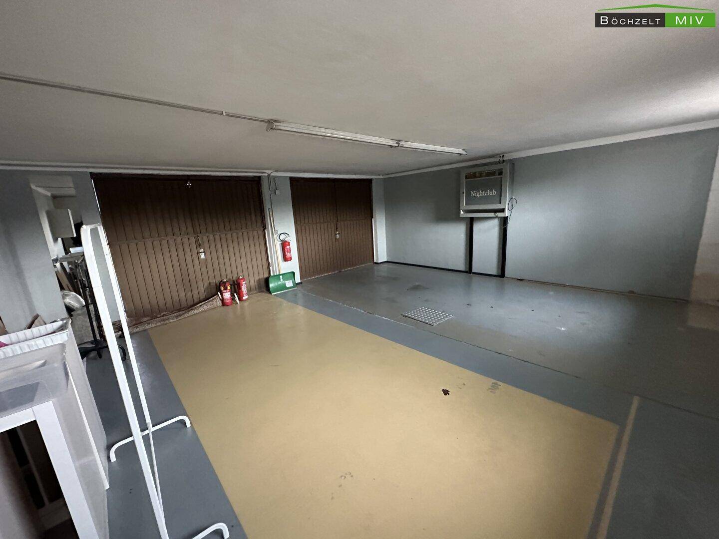 Geräumige Garage mit zwei großen Toren und einem robusten Bodenbelag, ideal für mehrere Fahrzeuge.