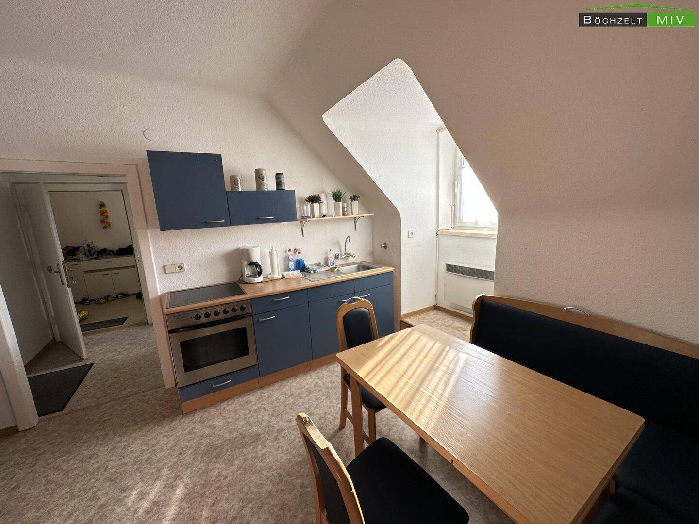Kleine Küchenzeile mit Essbereich in einer Dachgeschosswohnung mit schrägen Wänden.