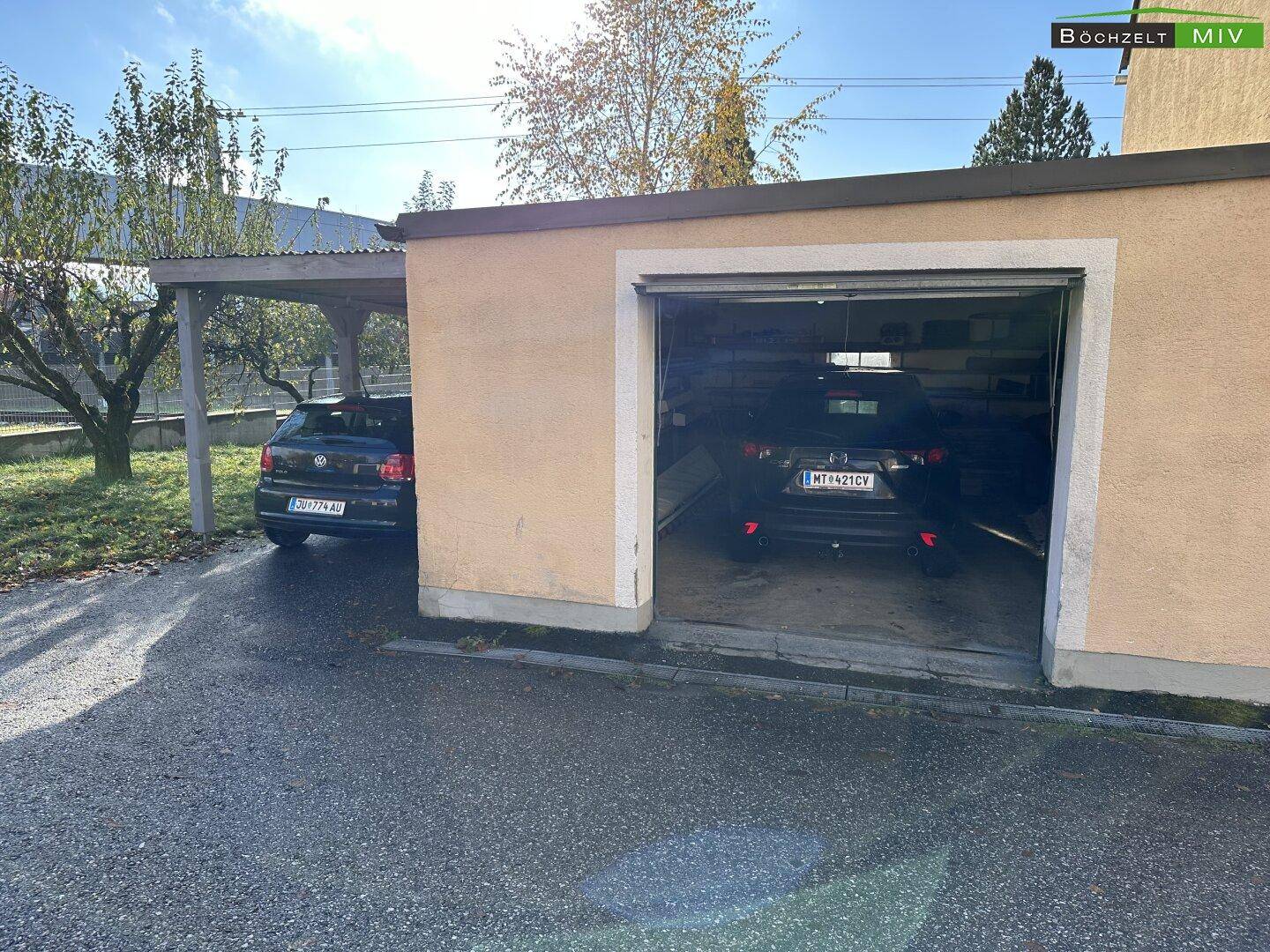 Garage mit einem Stellplatz und einem angrenzenden Carport für zusätzliche Fahrzeuge.