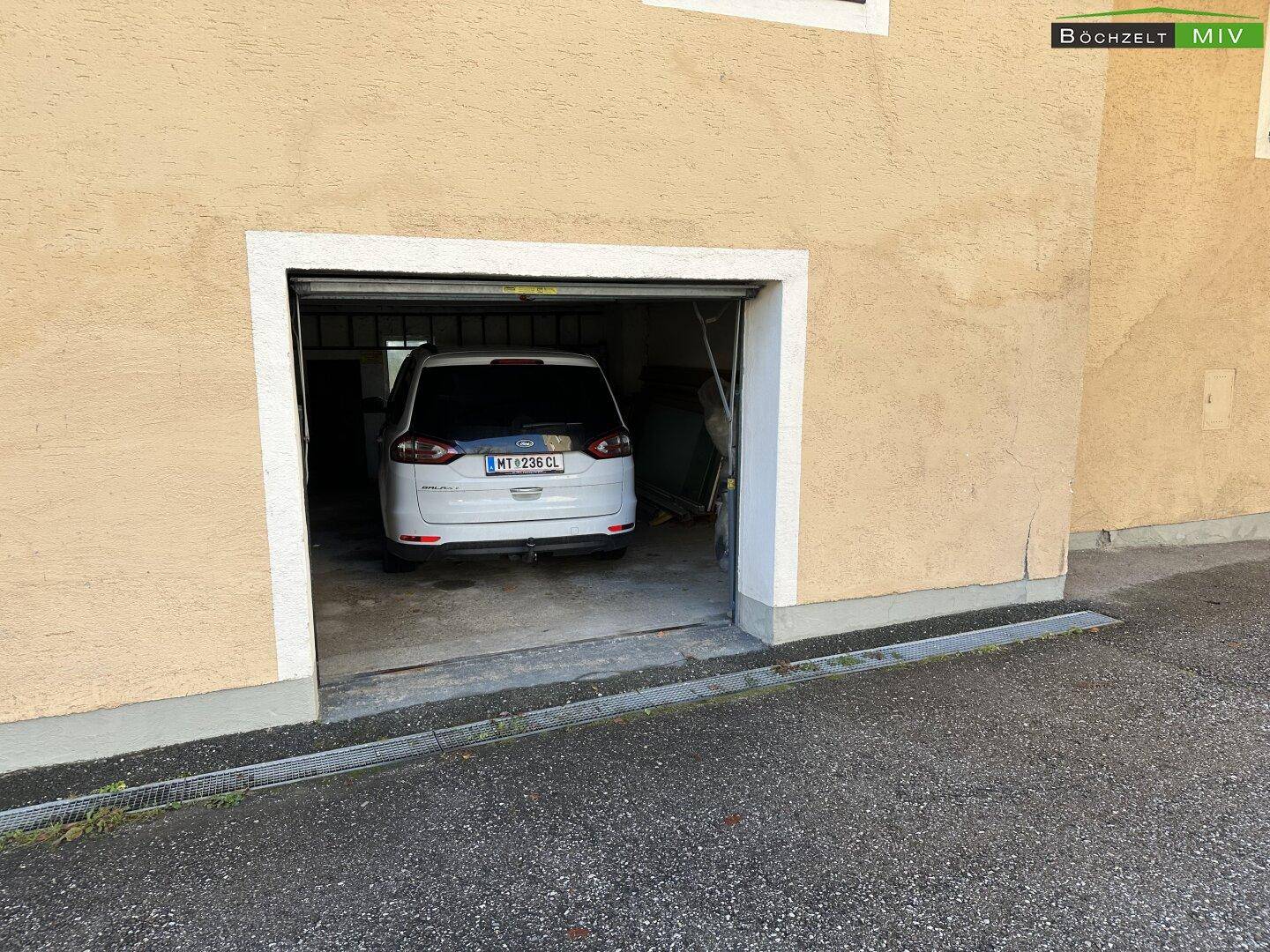 Einzelgarage mit einem geparkten Fahrzeug, Teil des Anwesens.