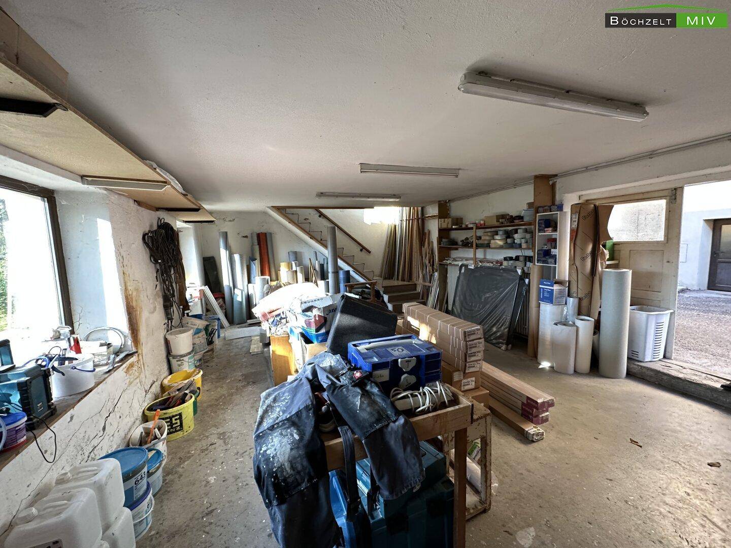 Helle Werkstatt oder Lagerhalle mit großen Fenstern und viel Platz für Materialien.